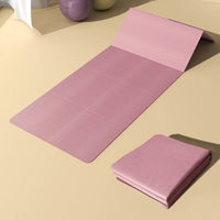 Tapis de Pilates rose pliable et confortable, sur un sol beige.